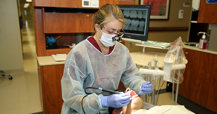 Dental hygienist performing a professional cleaning on a patient.