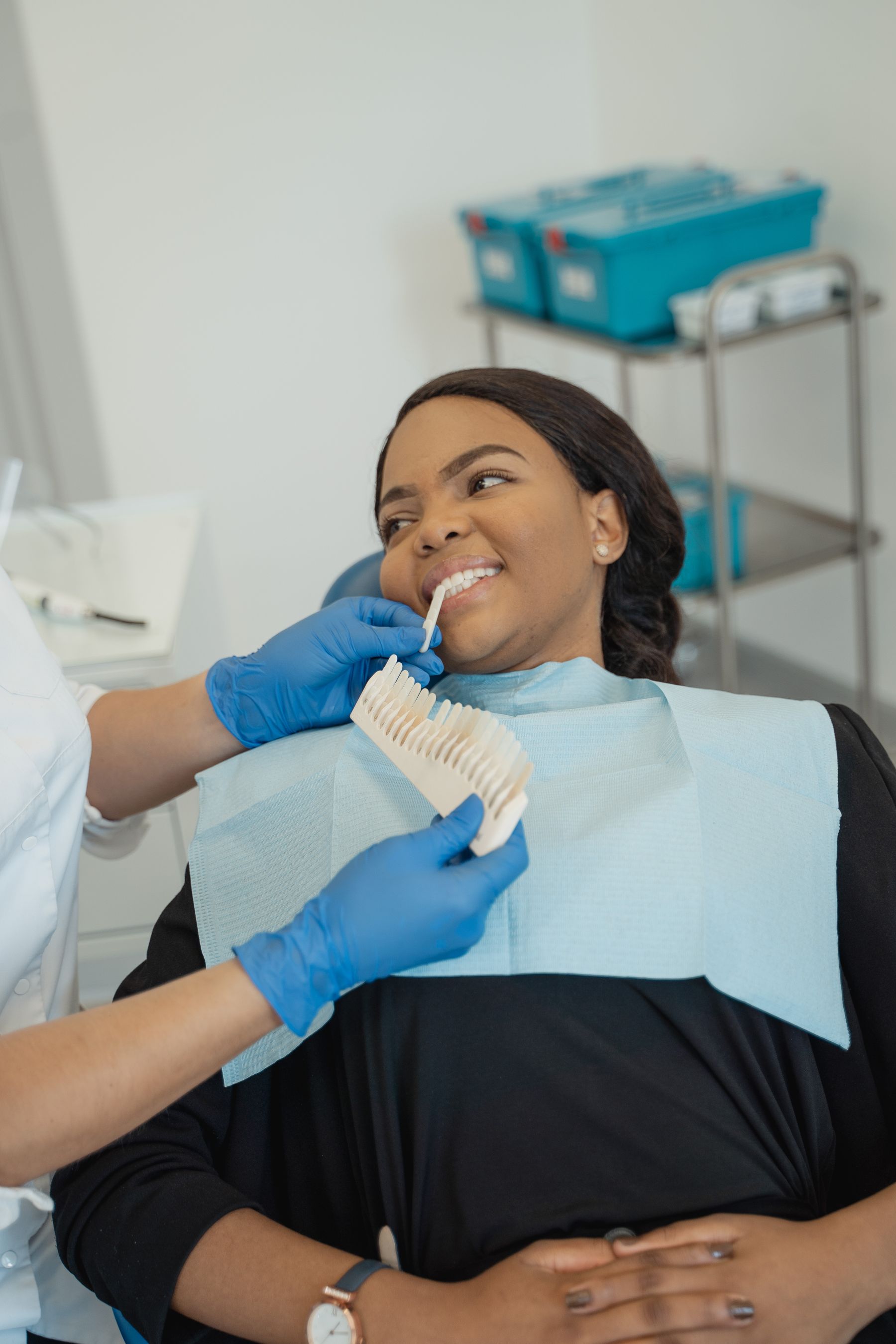 A smiling patient having her tooth shade matched during a dental appointment.
