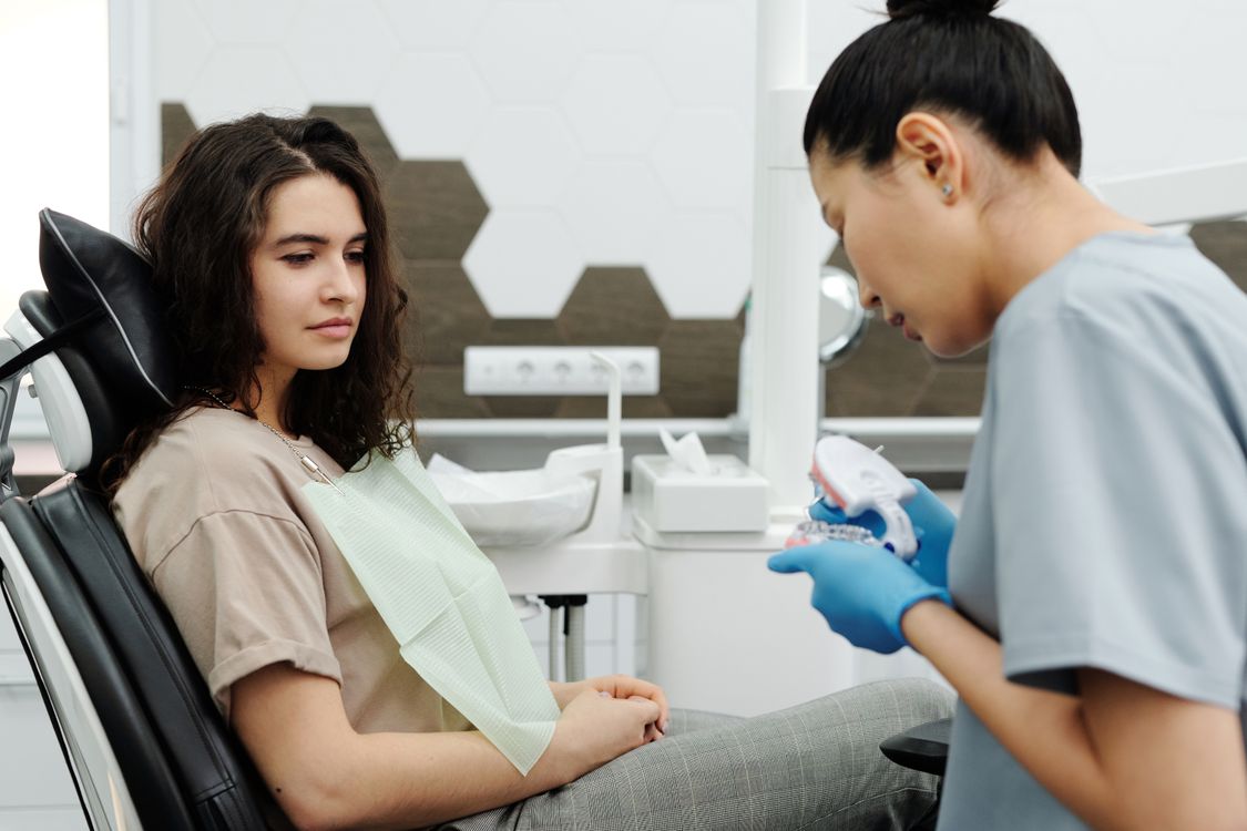 A patient listens as a dentist explains a dental model.